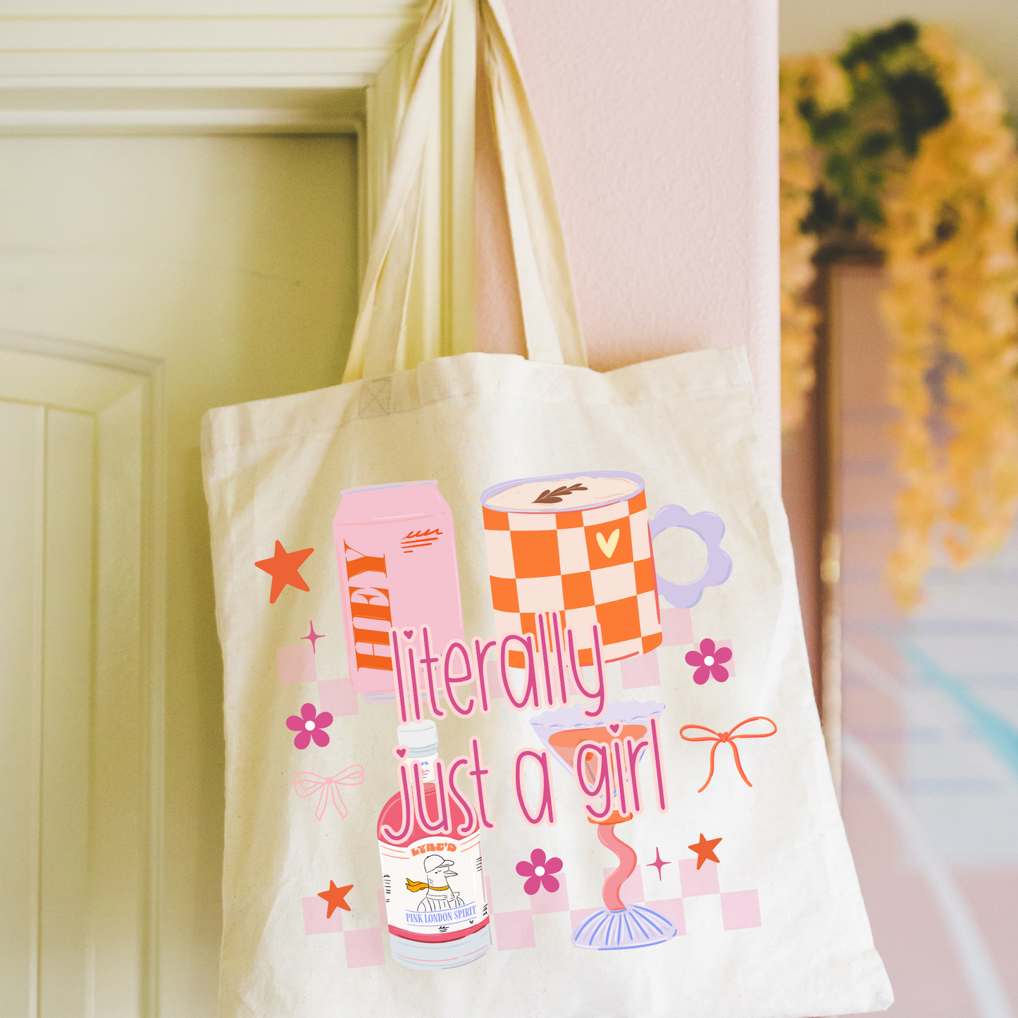 Tote bag with colorful literally just a girl graphics and text hanging on a door.