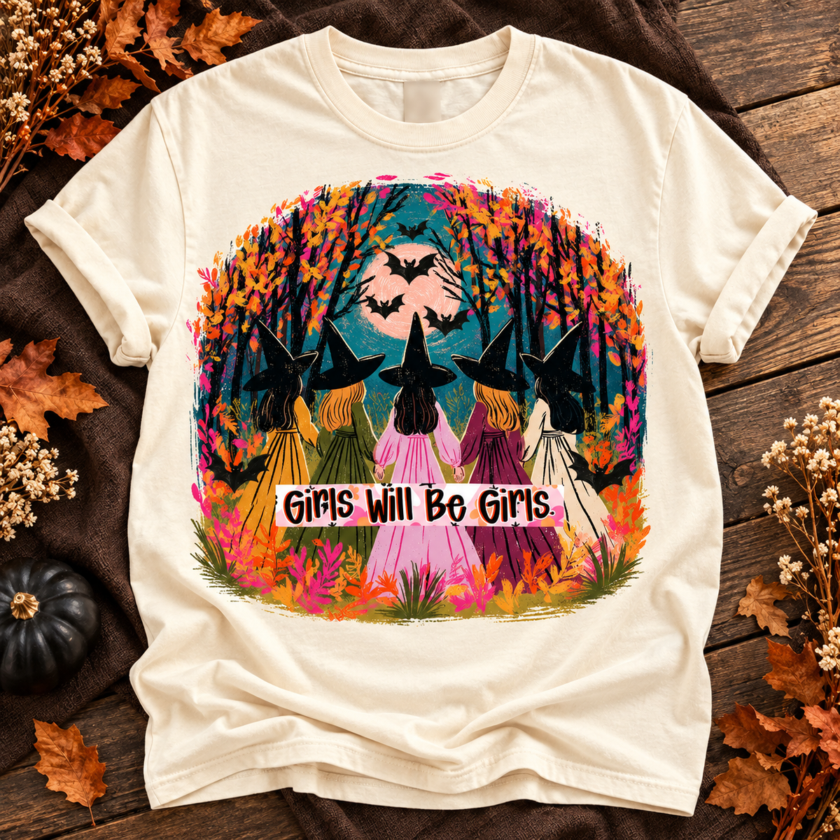 Ivory T-shirt with five witches walking beneath bats and autumn trees, Girls Will Be Girls design