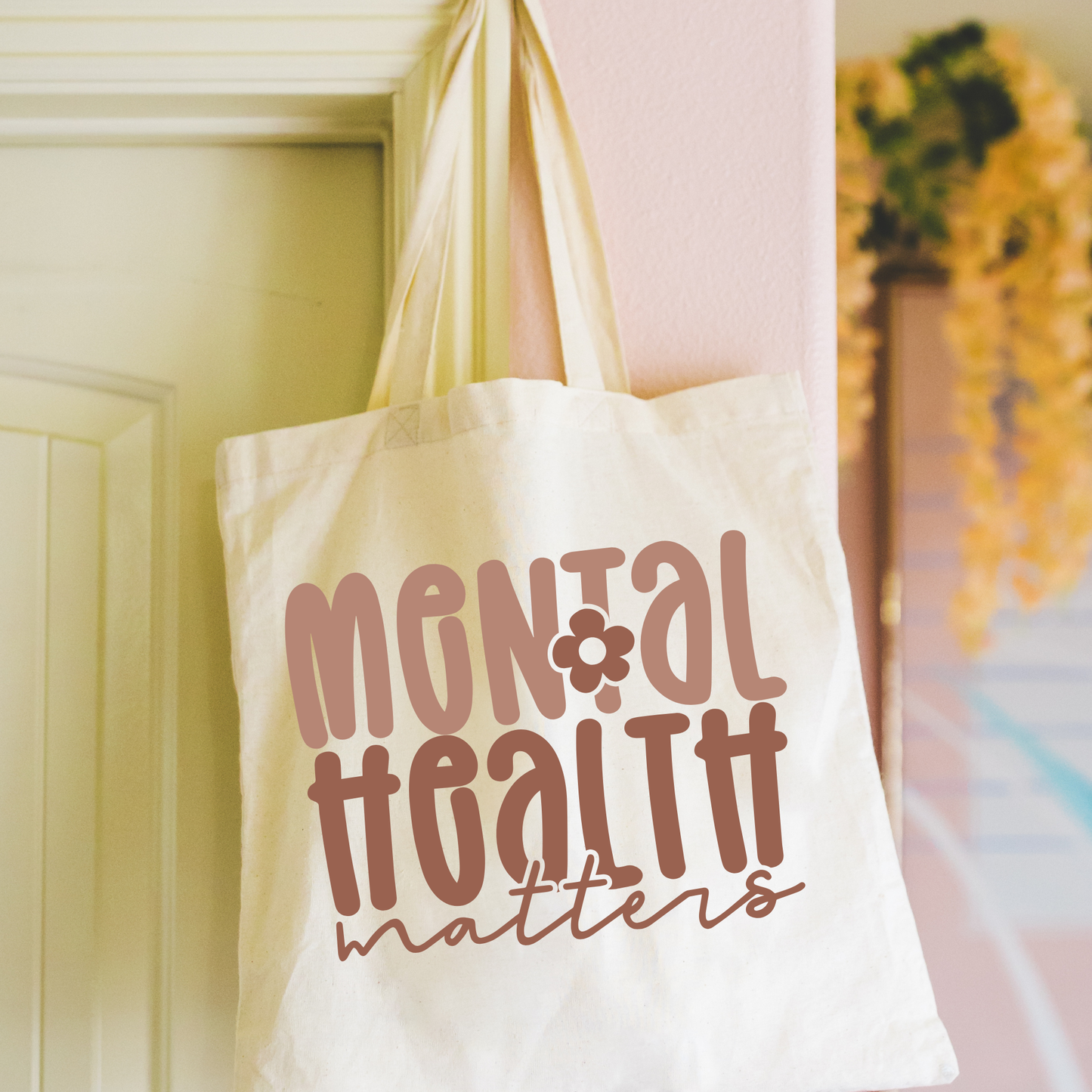 White tote bag with 'Mental Health Matters' text hanging on a door.