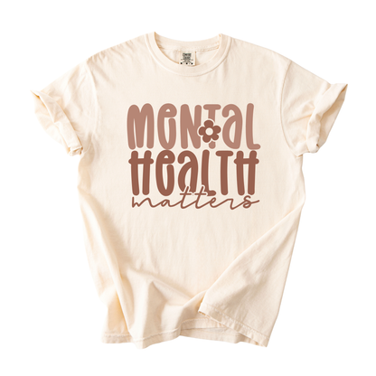 Beige t-shirt with 'Mental Health Matters' text on a white background