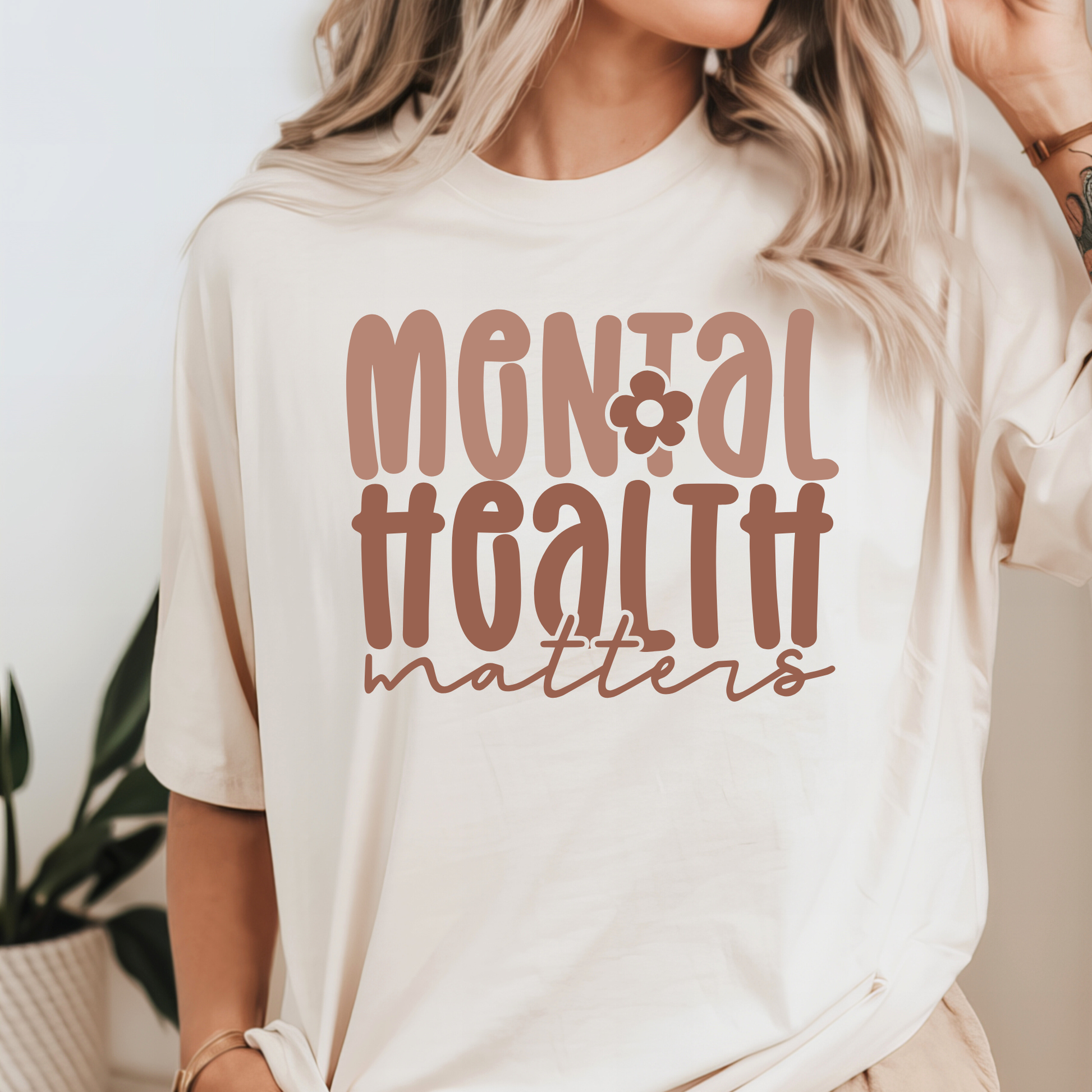 Woman wearing a cream Comfort Colors T-shirt with ‘Mental Health Matters’ printed in retro lettering.