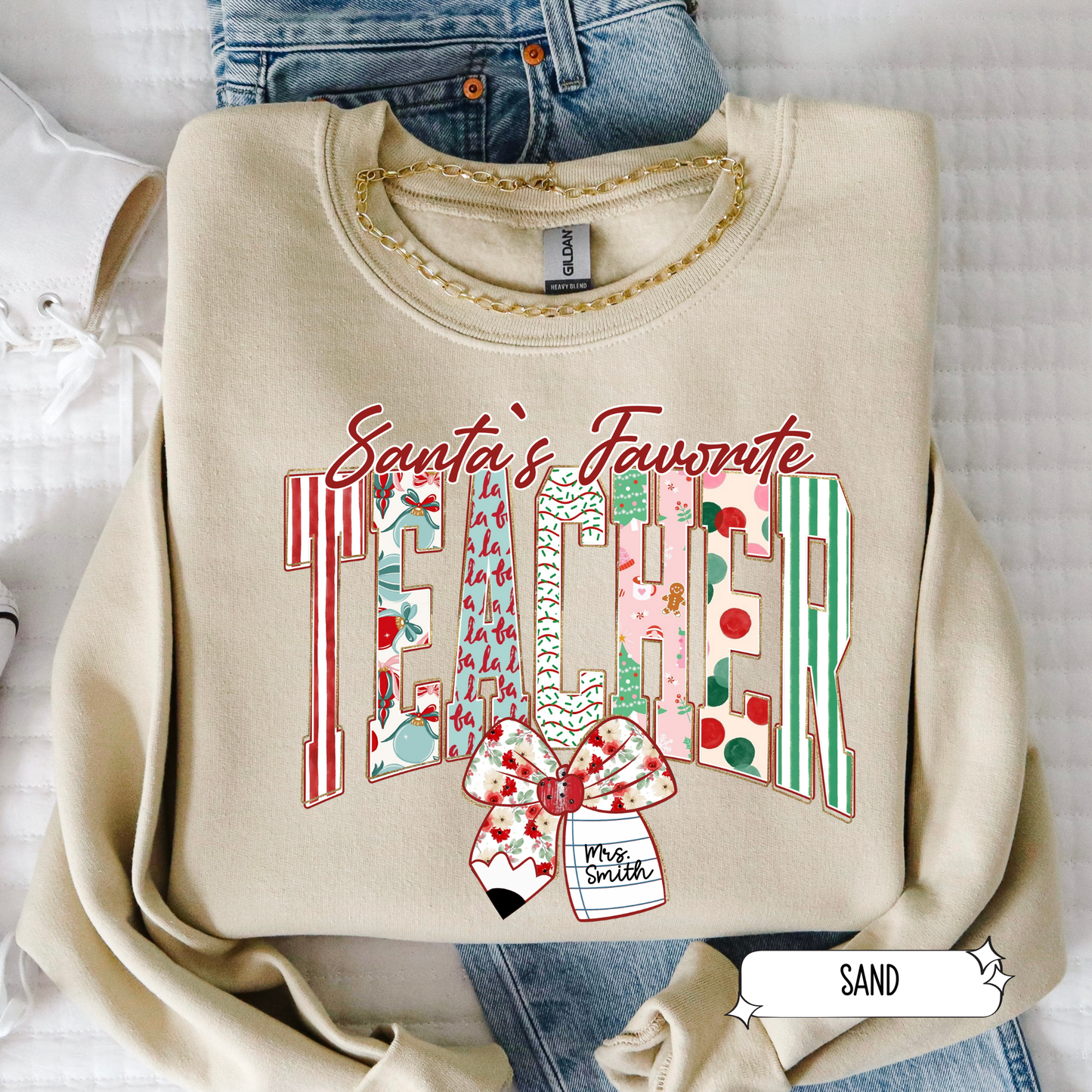 Sand color Santa’s Favorite Teacher Christmas sweatshirt with festive striped letters and bow, displayed in flat lay.