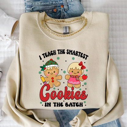 Sand color Smartest Cookies teacher Christmas sweatshirt with gingerbread characters and festive design, flat lay photo.