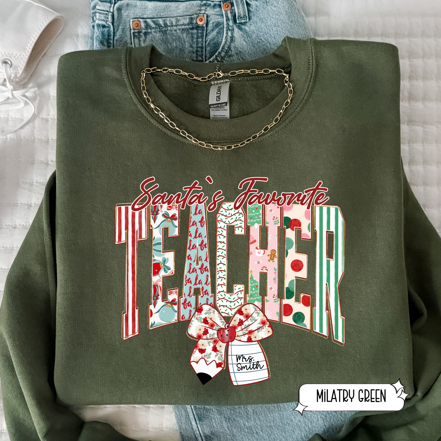 Military green Santa’s Favorite Teacher holiday sweatshirt with red and green striped teacher design in flat lay style.