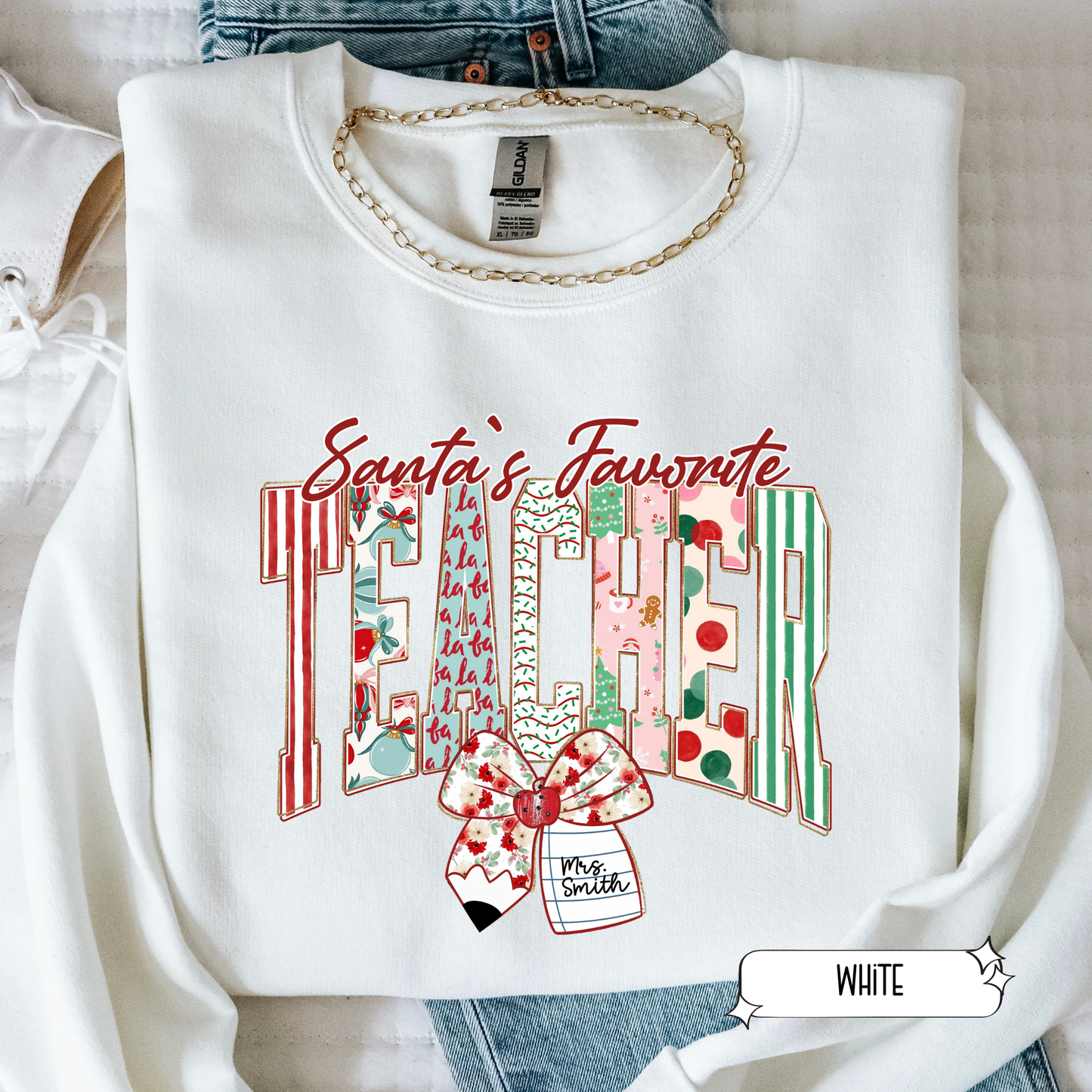White Christmas teacher sweatshirt with Santa’s Favorite Teacher design featuring colorful stripes and bow, flat lay photo.