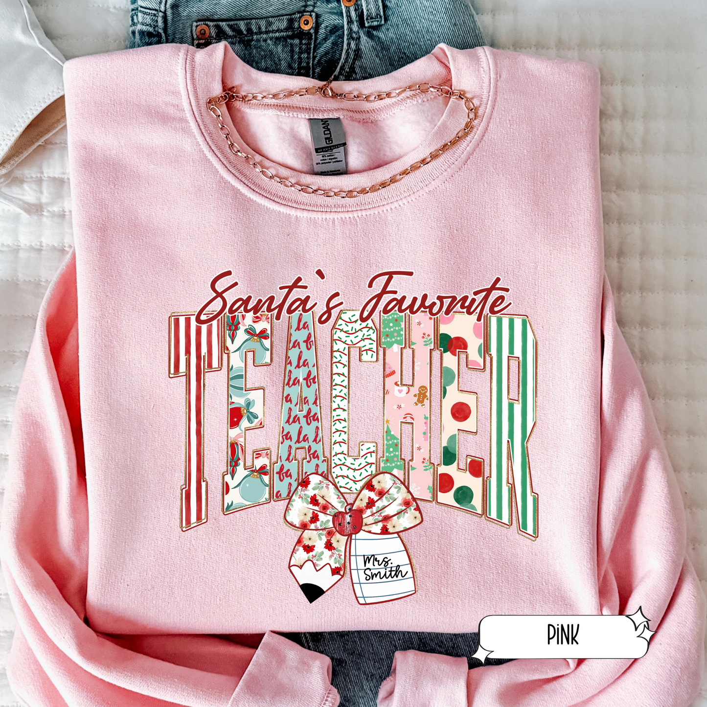 Pink Santa’s Favorite Teacher Christmas sweatshirt with cute festive striped letters and bow, displayed in flat lay.