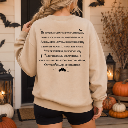 A woman viewed from behind wearing a beige crewneck sweatshirt with a black autumn-themed poem printed on the back, standing on a decorated porch with pumpkins and lanterns.