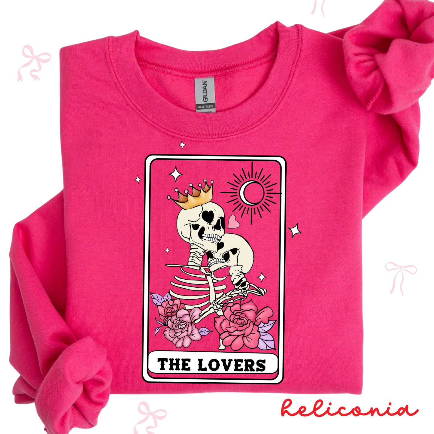 Pink sweatshirt with a skeleton design labeled 'The Lovers' by Heliconia on a white background.