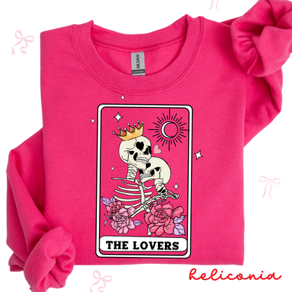 Pink sweatshirt with a skeleton design labeled 'The Lovers' by Heliconia on a white background.