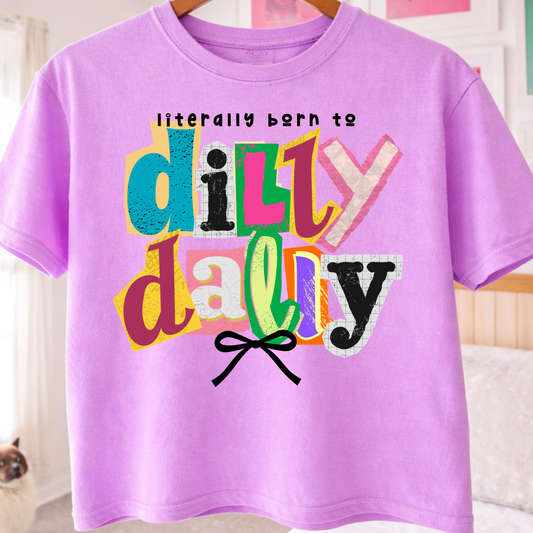 Neon Purple t-shirt with colorful text 'literally born to dilly dally' on a hanger.
