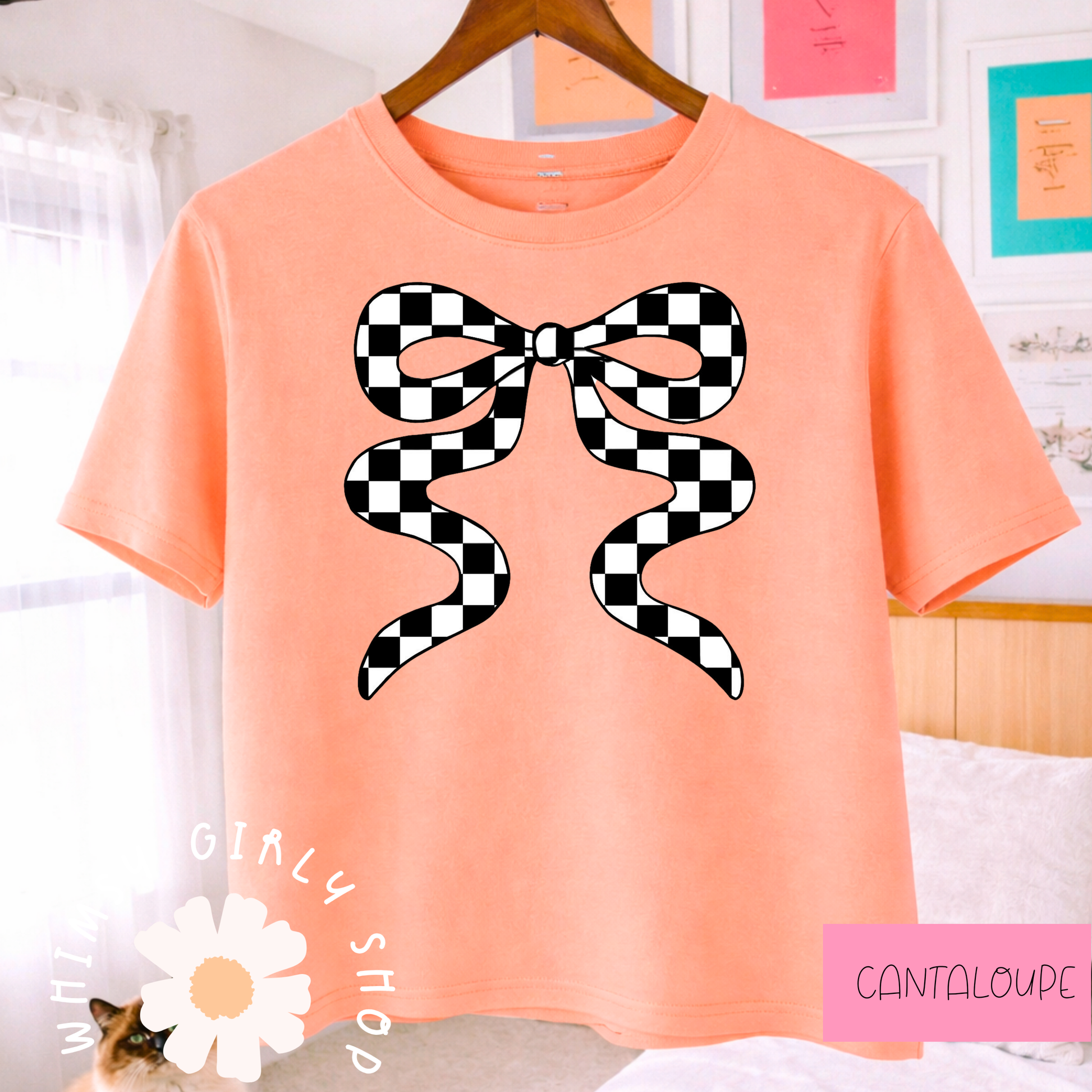 cantaloupe t-shirt with a black and white checkered bow design, hanging on a wooden hanger.