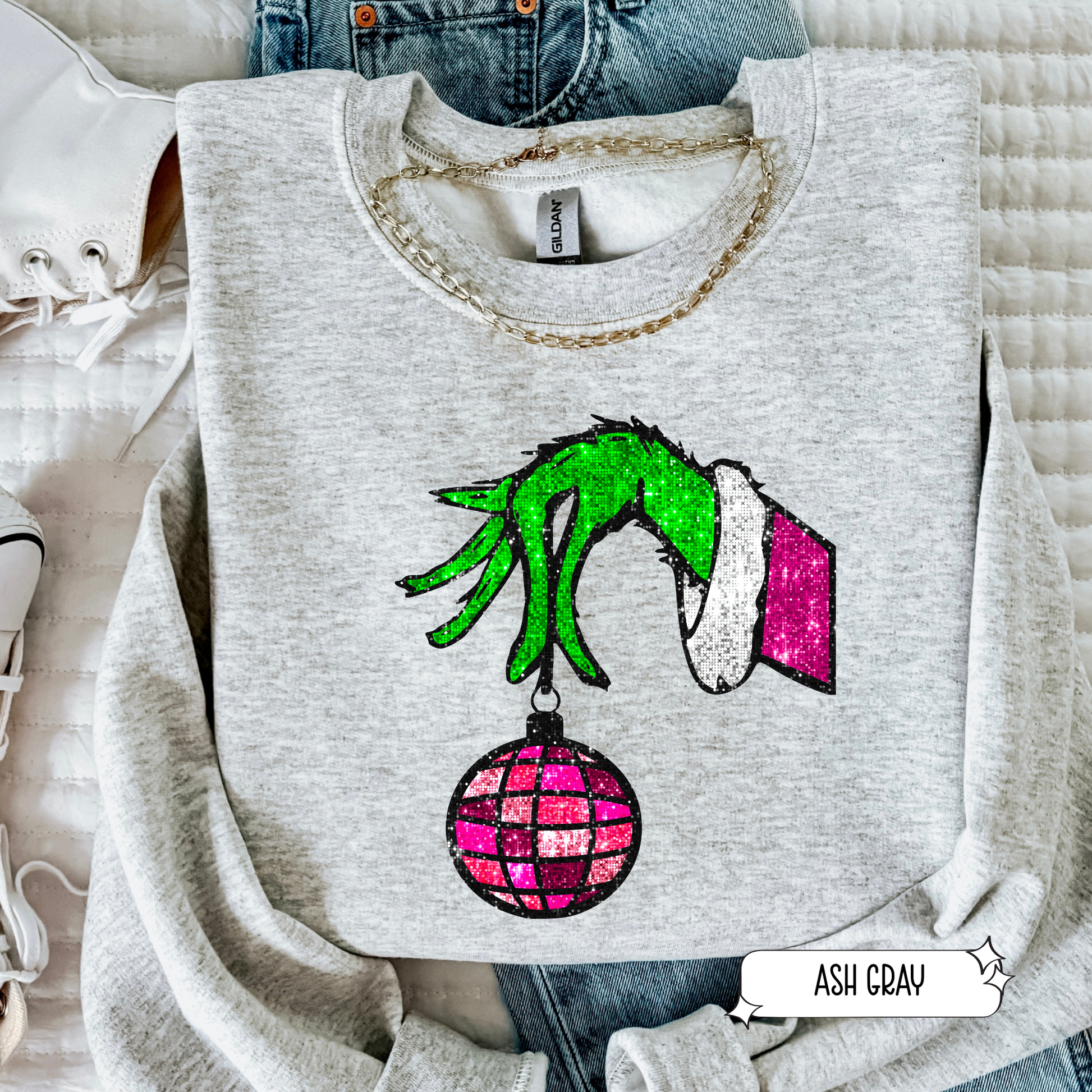 Gray sweatshirt with Grinch hand holding a ornament design on a light background