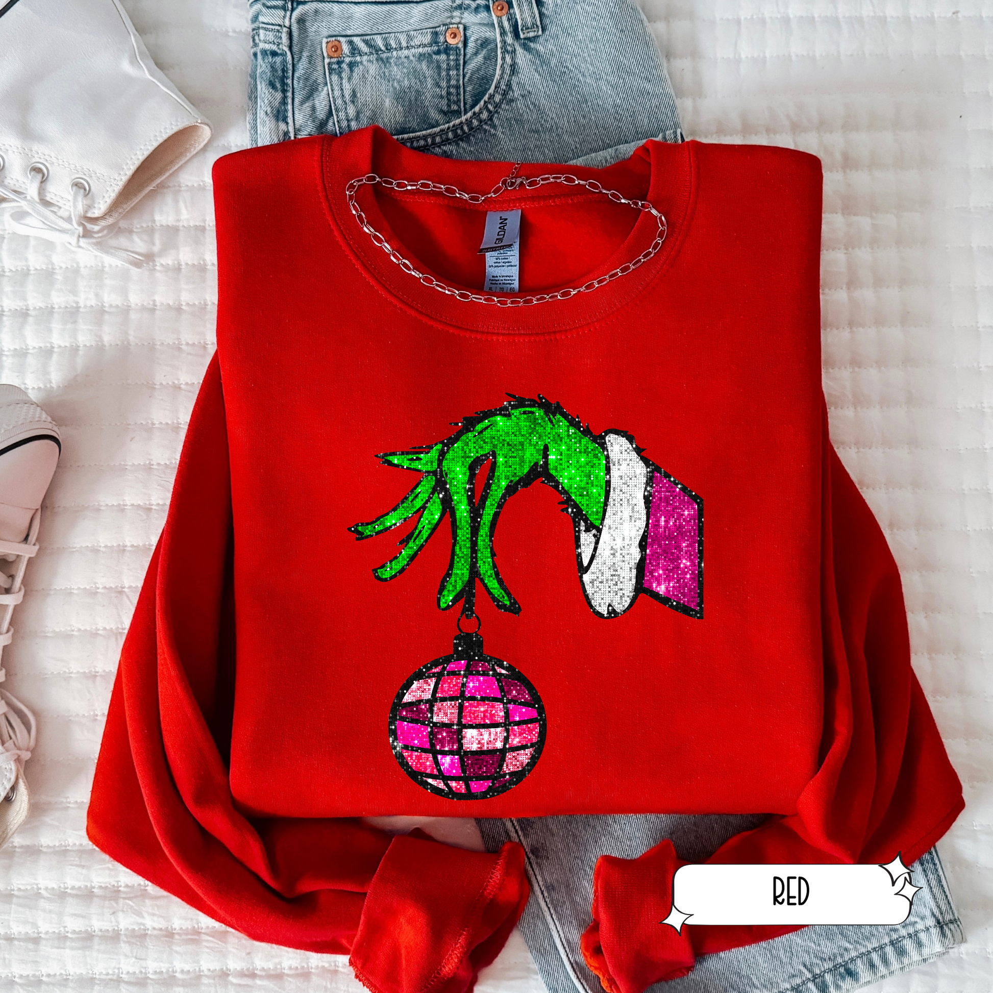 Red sweatshirt with Grinch design on a white surface