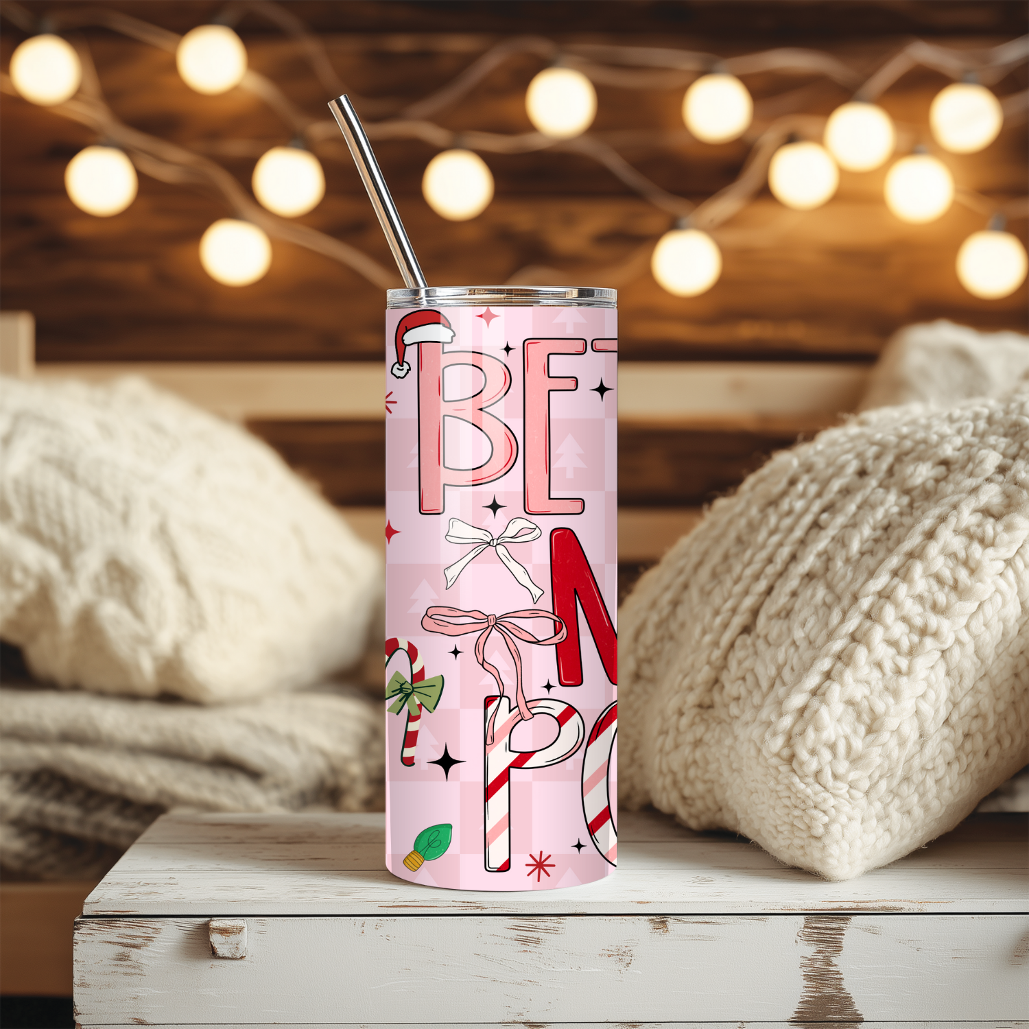 Checkered tumbler with 'BETTER NOT POUT' text and festive design on a wooden surface with blurred lights in the background.
