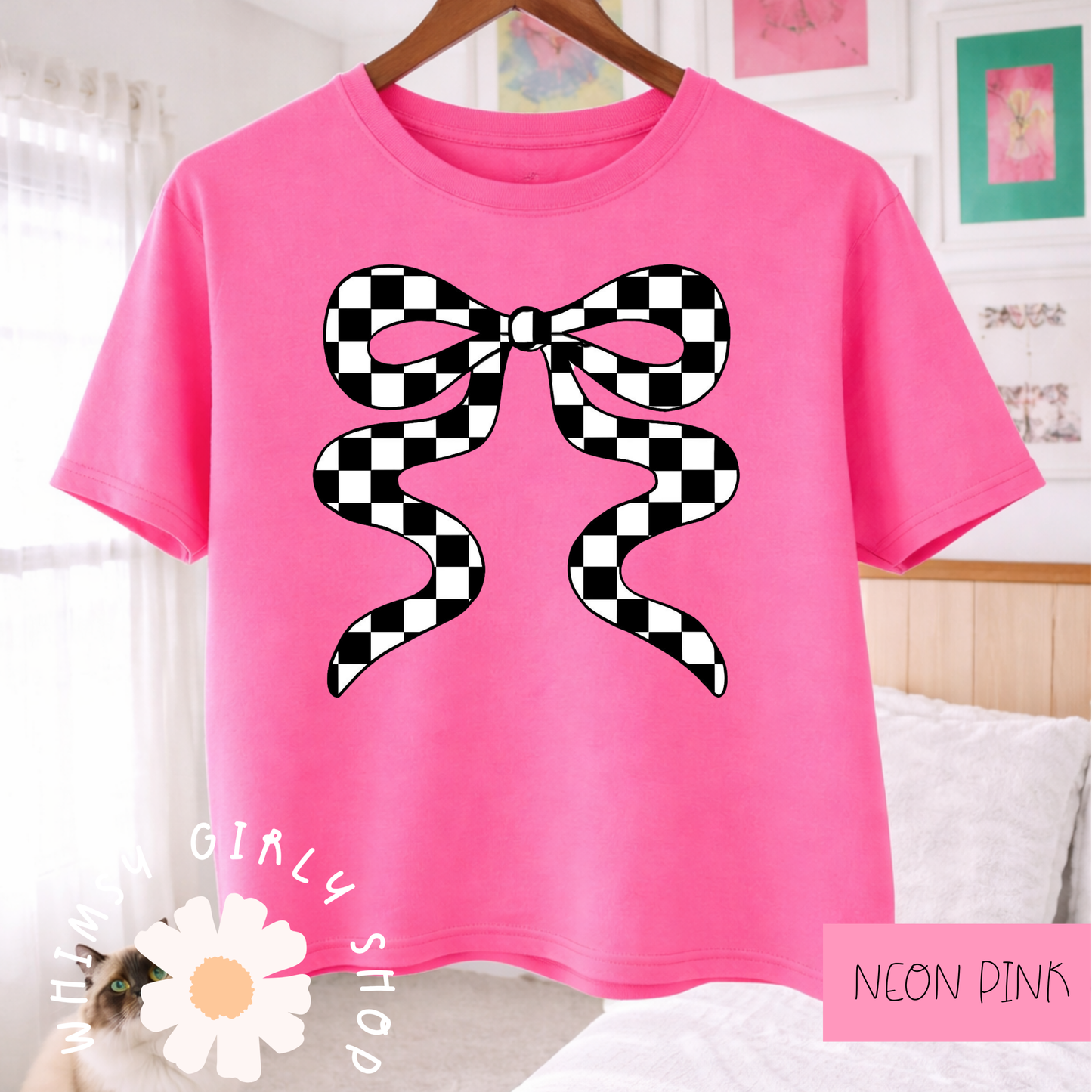 Neon pink t-shirt with a black and white checkered bow design, hanging on a wooden hanger.