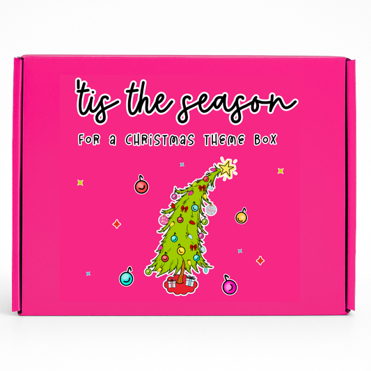 Pink Christmas-themed gift box with illustrated Christmas tree. includes Tshirt, Earrings, Cup, and Christmas Ornament