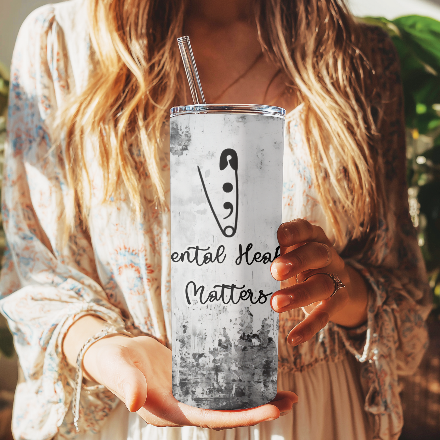 Person holding a tumbler with 'Mental Health Matters' text and logo.