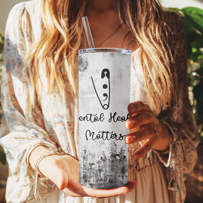 Person holding a tumbler with 'Mental Health Matters' text and logo.