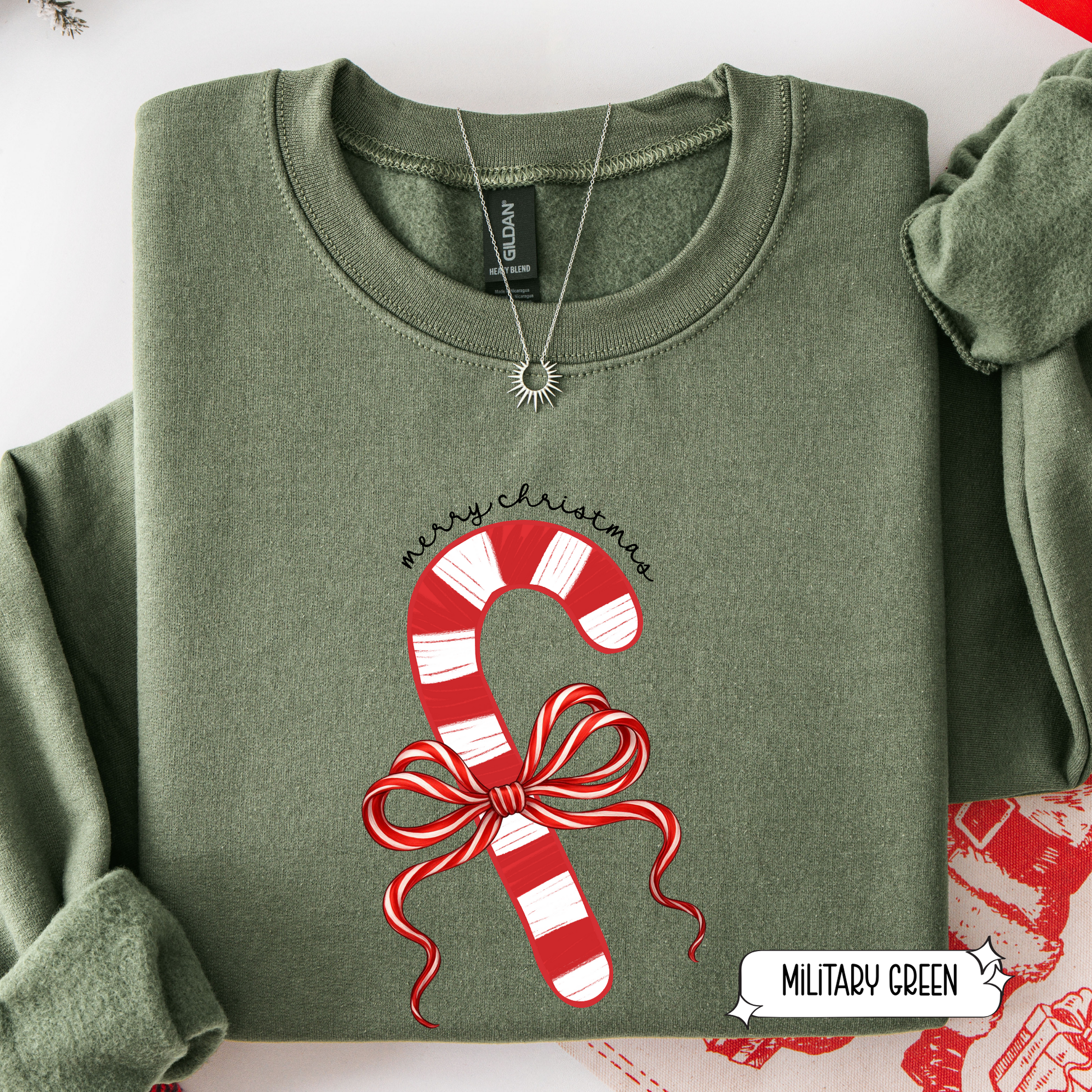 Folded green sweatshirt with candy cane design and 'Merry Christmas' text on a white background.