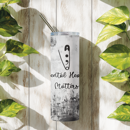 Tumbler with 'Mental Health Matters' text and logo on a wooden surface with leaves.