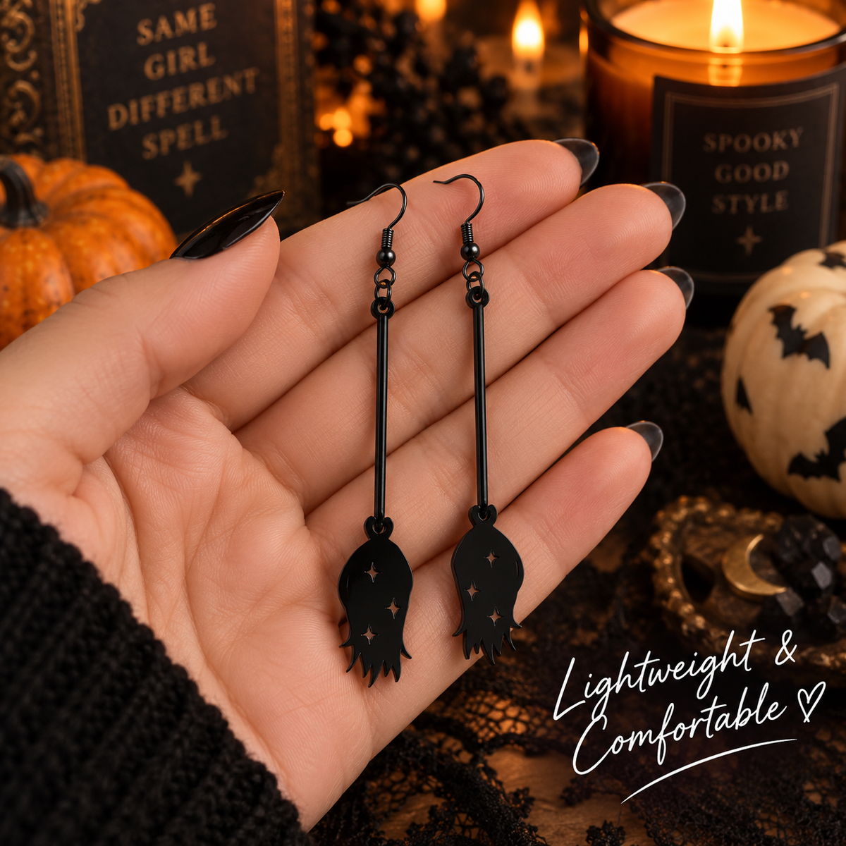 Black spooky dangle earrings held in hand