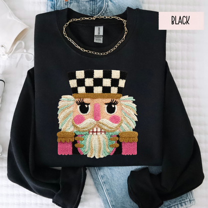 Black sweatshirt with colorful faux yarn embroidered design of a character wearing a checkered hat on a light background.