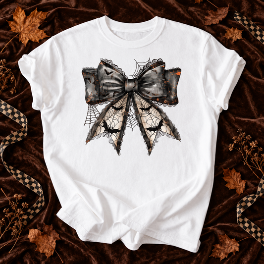 White T-shirt featuring Spider Web Bow graphic on a dark autumn flat lay