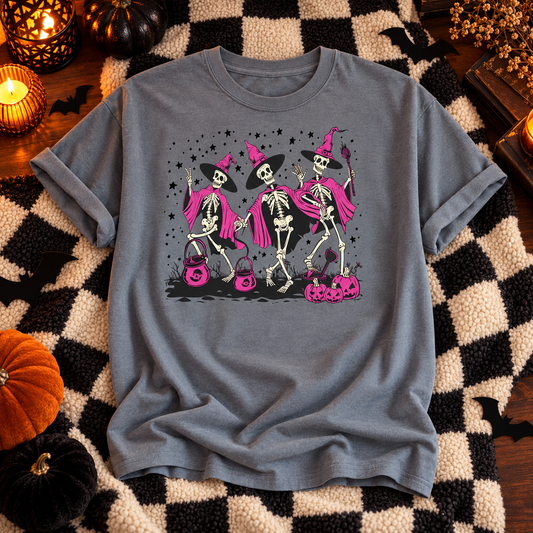 Gray Ghoul Squad T-shirt with three pink-cloaked skeleton witches and pumpkins on a checkered throw
