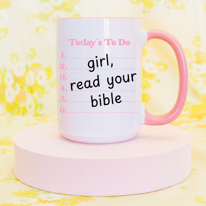 Pink 15oz Christian motivational mug with ‘girl, read your bible’ design displayed on a pastel stand.