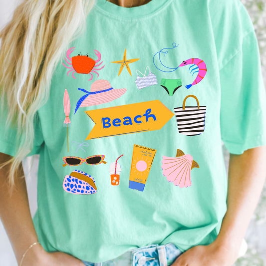 Person wearing a light green t-shirt with beach-themed graphics and the word 'Beach'.