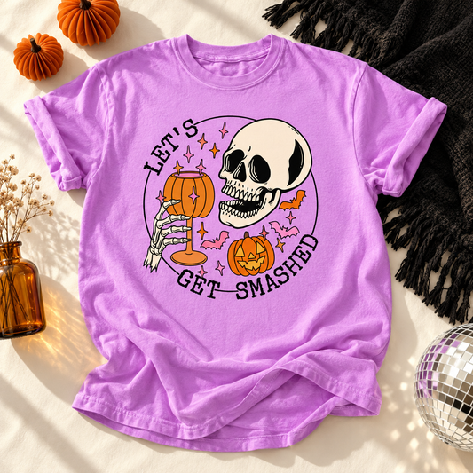 Neon Violet T-shirt featuring Let's Get Smashed skeleton with pumpkin drink graphic on a Halloween flat lay