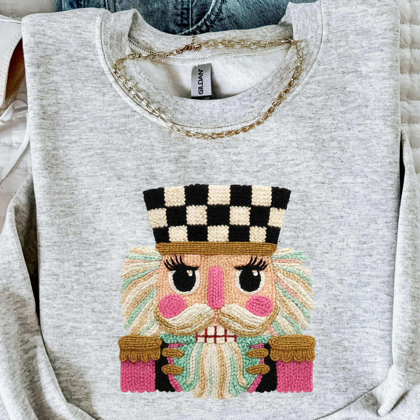 Gray sweatshirt with faux embroidered face design on a white background