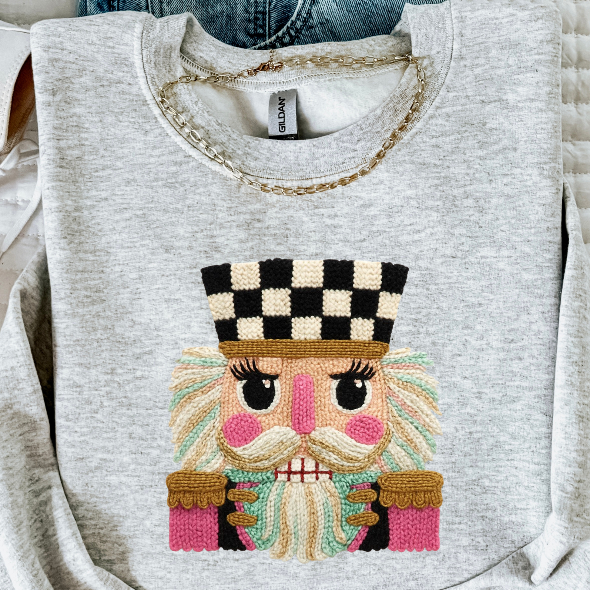 Gray sweatshirt with faux embroidered face design on a white background