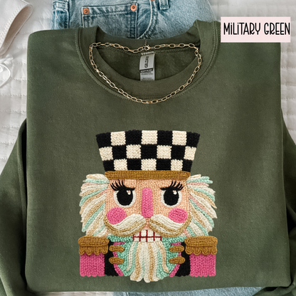Military green sweatshirt with faux yarn embroidered face design on a light gray background