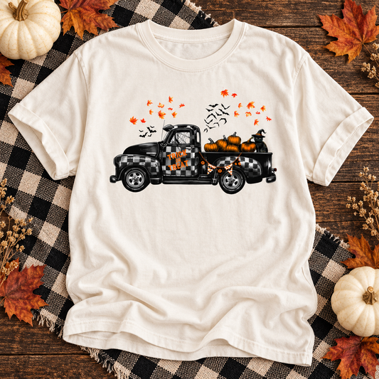 Ivory T-shirt featuring Trick or Treat Halloween truck graphic on an autumn flat lay